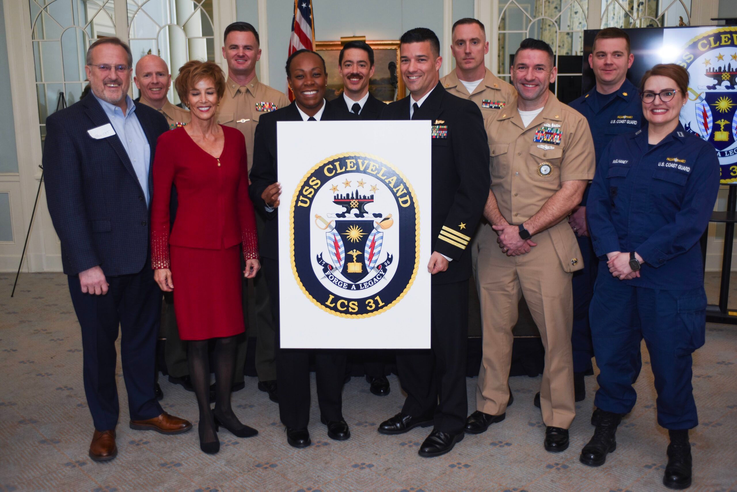 Cmdr. Bruce Hallett, commanding officer of the Freedom-class Littoral Combat Ship USS Cleveland (LCS-31) and Command Master Chief Carla Bellamy take a group photo with the Cleveland Legacy Foundation and active duty service members after revealing the ships crest with Friday, April 5, 2024.